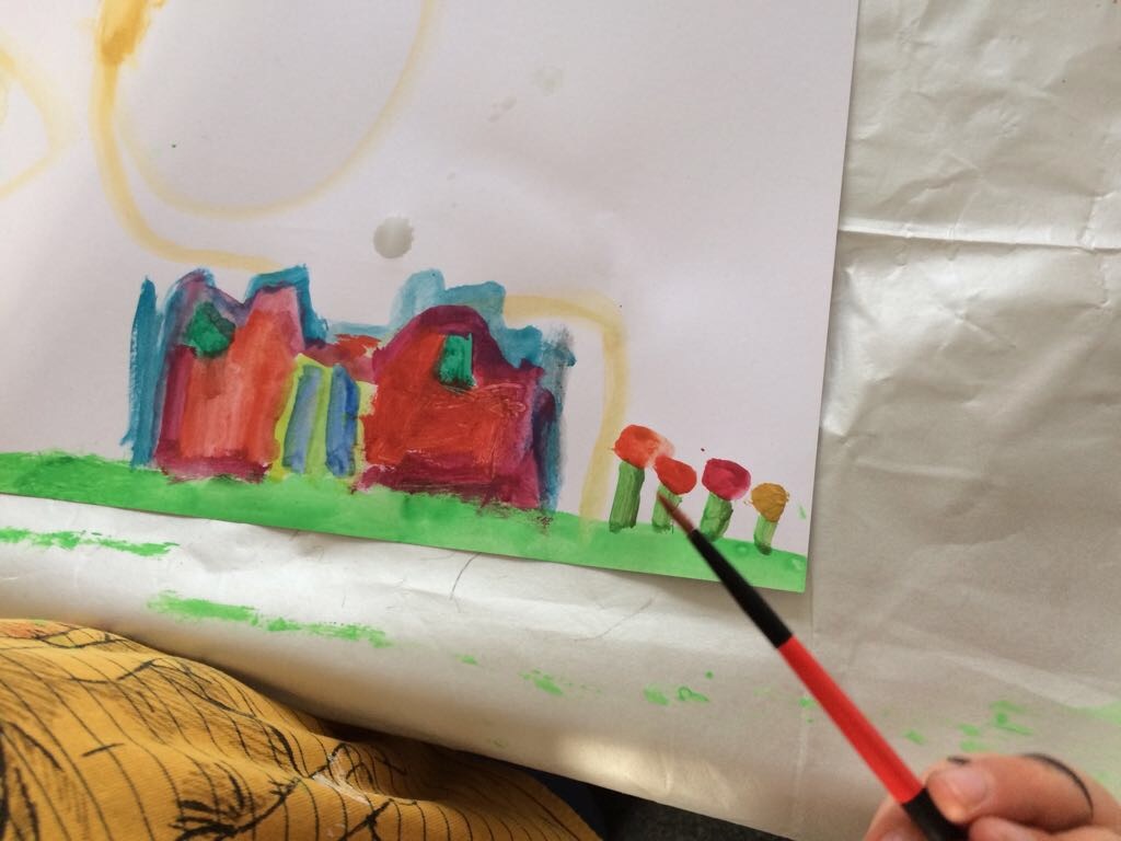 Een kind schildert met waterverf een vertelplaat voor de kamishibai.